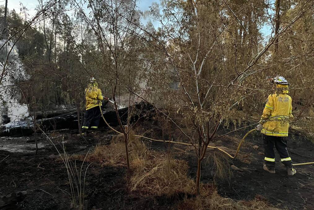 NSW Rural Fire Service crew dousing embers and burning logs at a Gilgandra grassfire. Picture by Gilgandra Rural Fire Service