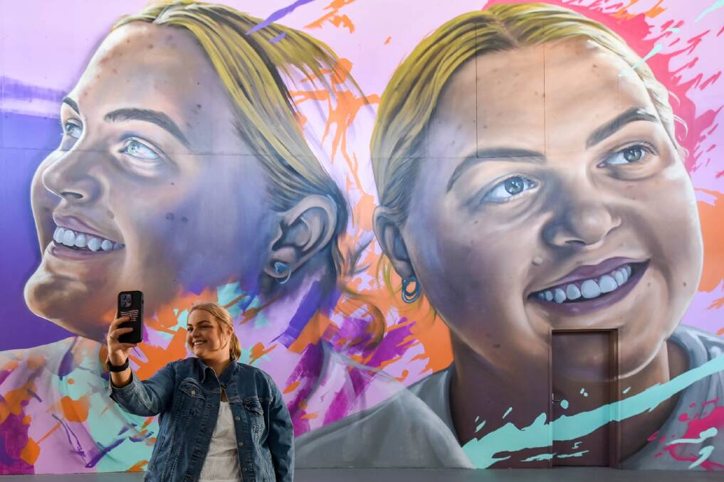 Molly Croft stands in front of a mural depicting her at Accor Stadium in Sydney, in recognition of her fundraising efforts for The Children's Hospital at Westmead. Picture supplied