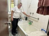 Irene Thompson in her bathroom at her Dubbo Homes NSW, next to the bath she has had to climb in to have a shower - despite having had a knee and hip operation. Picture by Belinda Soole