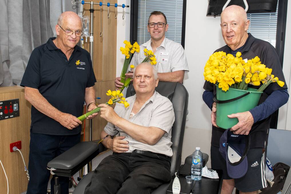 Cancer Council volunteer Phil Peak offering a bunch of flowers to patient Nigel Tyack, alongside nursing unit manager Tim Williams and volunteer Peter Hargreaves. Picture by Belinda Soole