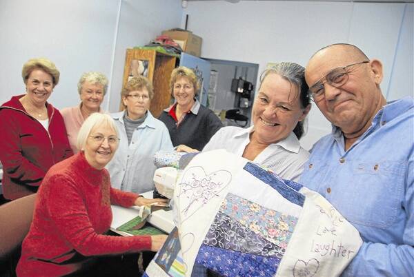 Di McKeowen, Dianne Lee, Carolyn Willis, Cheryl Royal, Jean Thurston, Sandy and Brian Morris with one of the quilts bound for Queensland flood victims.